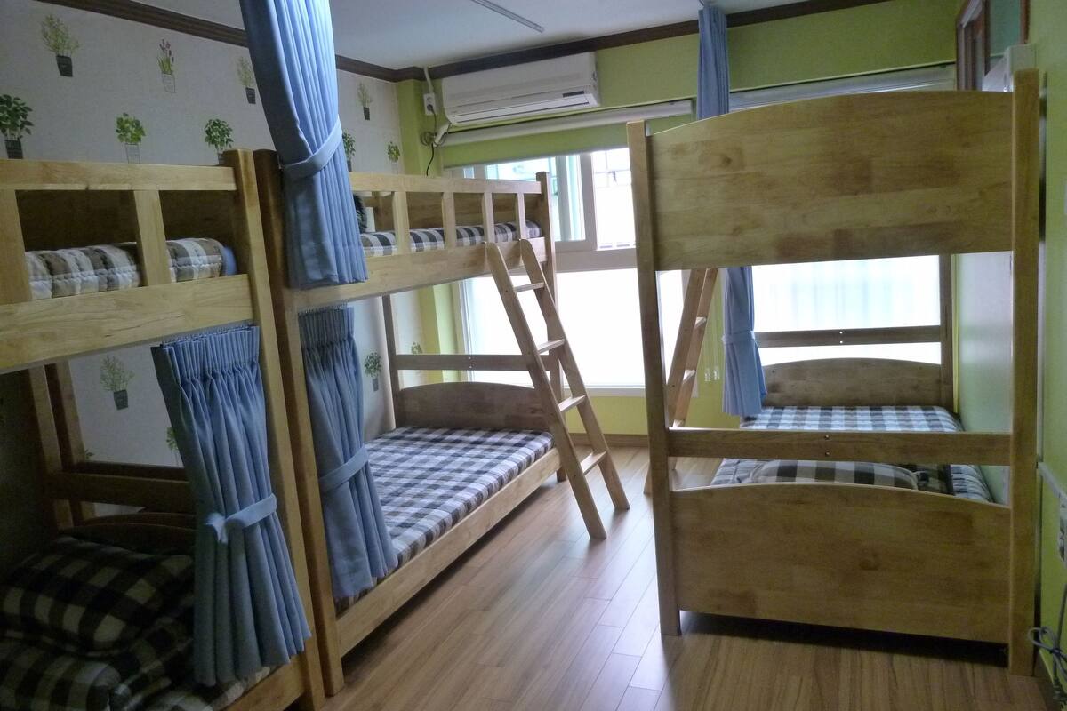 Une chambre avec un lit superposé en bois, une literie à carreaux et une échelle.