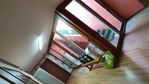 A room with a sloped ceiling, a skylight, a wooden floor, and a view of a red building outside. - Popcorn Hostel Nampodong (Busan)