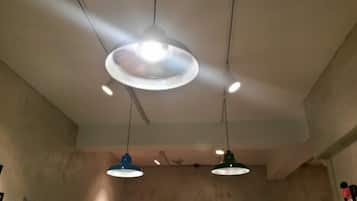 A ceiling with three pendant lights, one large and two smaller, in a room with plain walls and a visible electrical outlet.