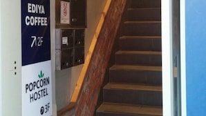 A staircase leading to a second floor with signs for Ediya Coffee and Popcorn Hostel. - Popcorn Hostel Nampodong (Busan)