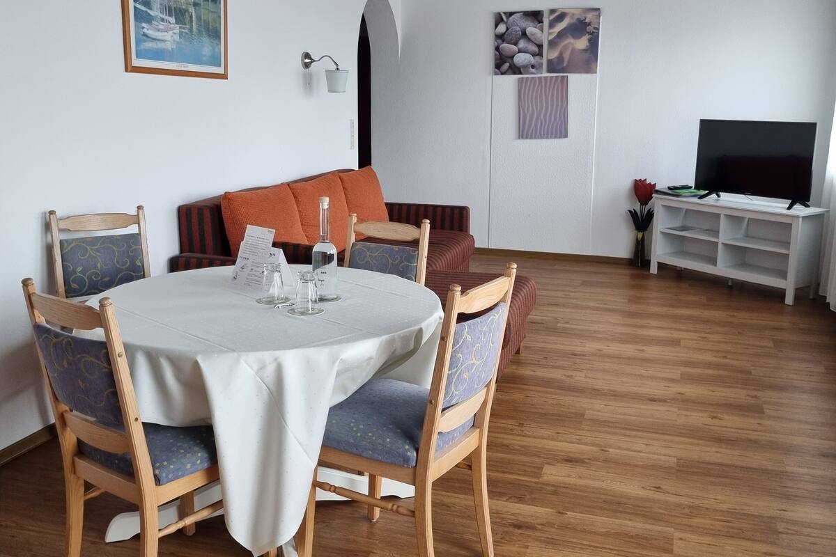 A dining area with a round table, chairs, and a television in the background.