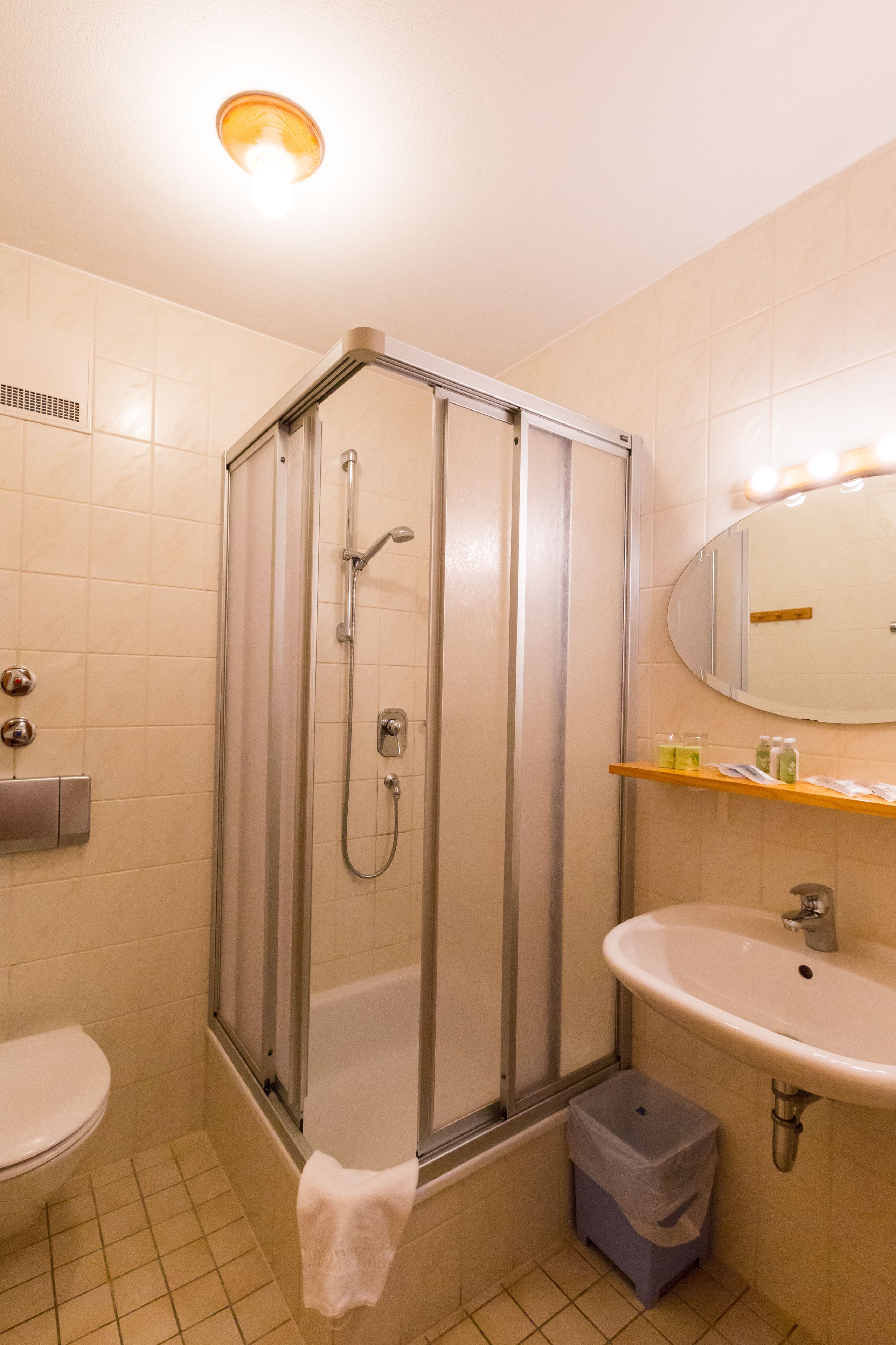 Ein Badezimmer mit einer Duschkabine aus Glas, einem Waschbecken und einem beleuchteten Spiegel.