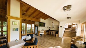 A spacious living area with wooden furniture, a dining table, and a staircase leading to another level.