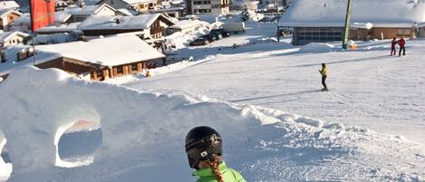 A ski resort with snow-covered mountains in the background, a ski lift, and a person skiing.