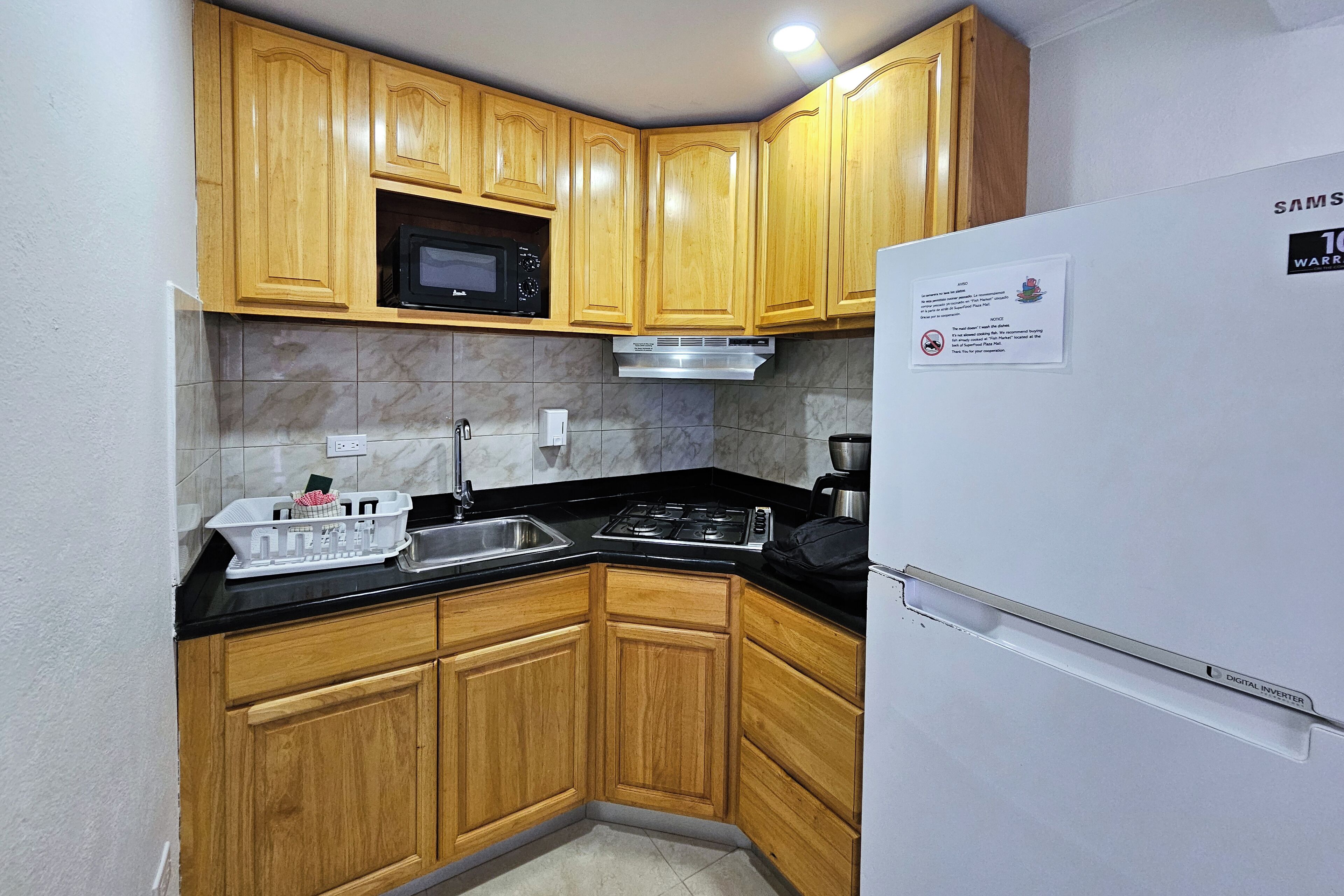 A compact kitchen with wooden cabinets, a microwave, a stove, and a refrigerator.