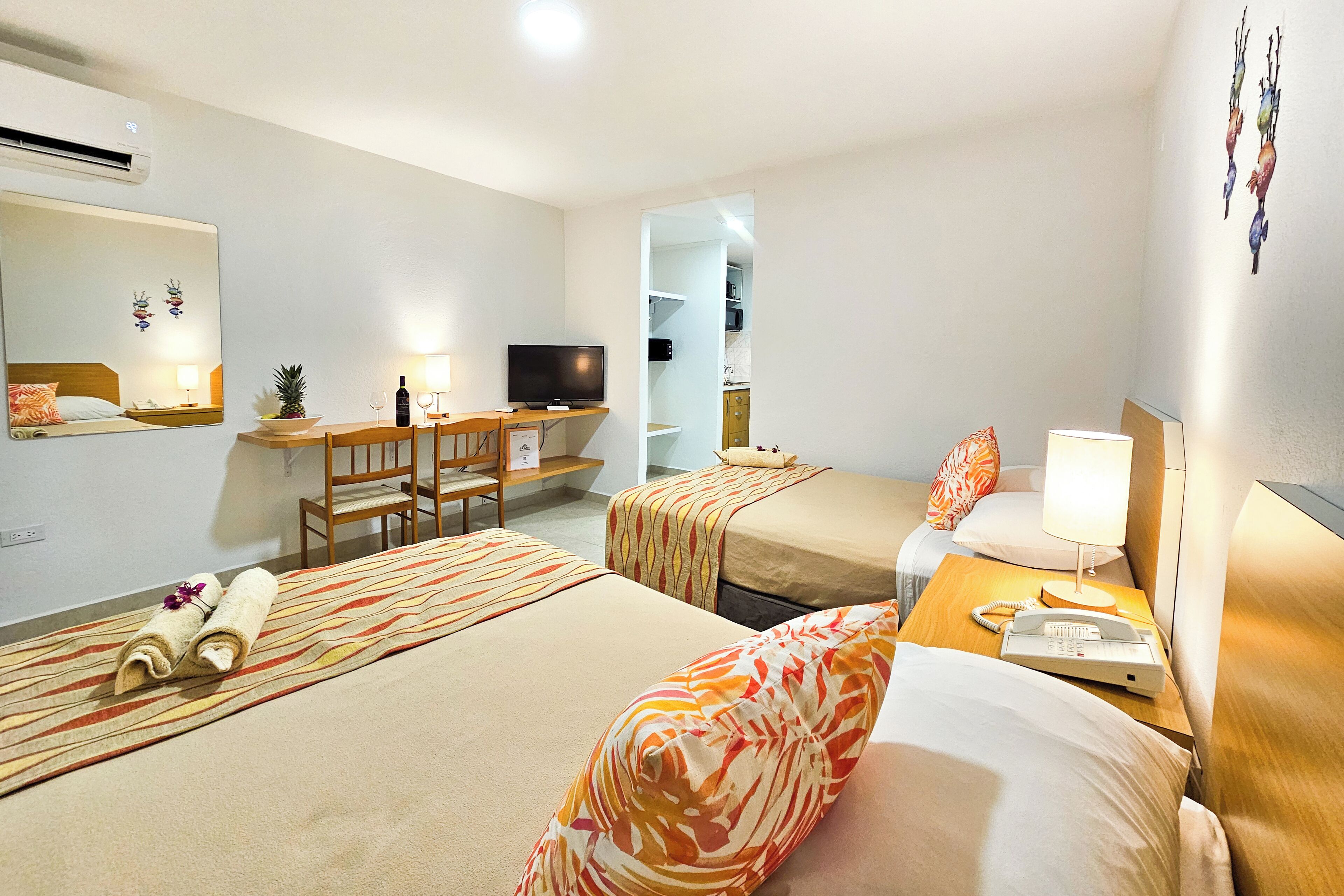Habitación de hotel con dos camas, un escritorio con computadora, televisor y teléfono.