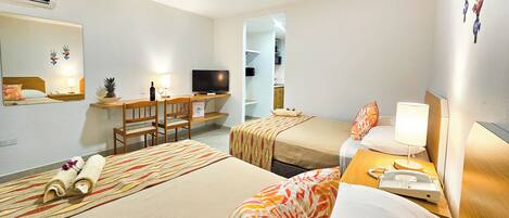 Habitación de hotel con dos camas, un escritorio con computadora, televisor y teléfono.