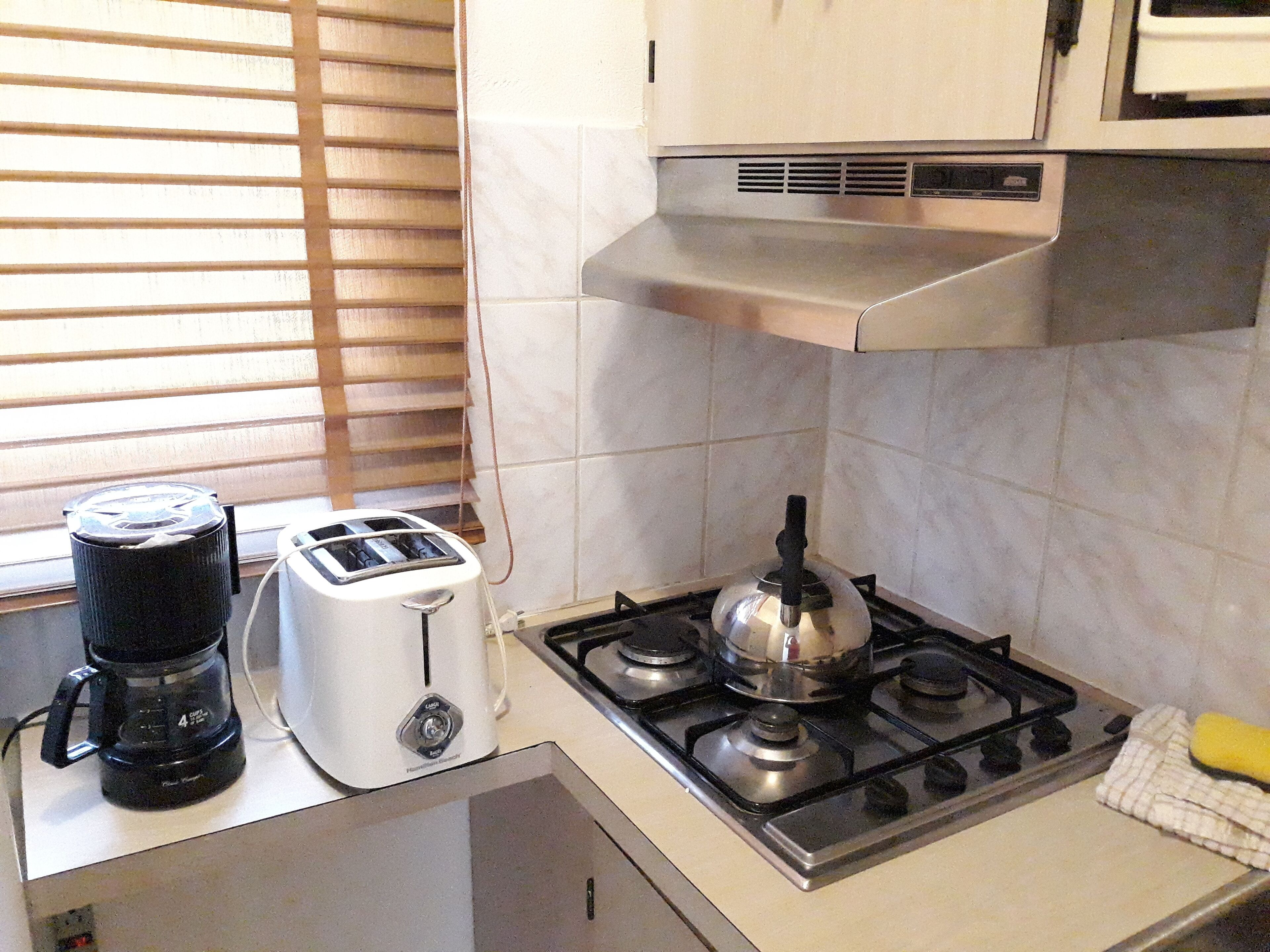 A kitchen with a gas stove, a toaster, and a coffee maker.