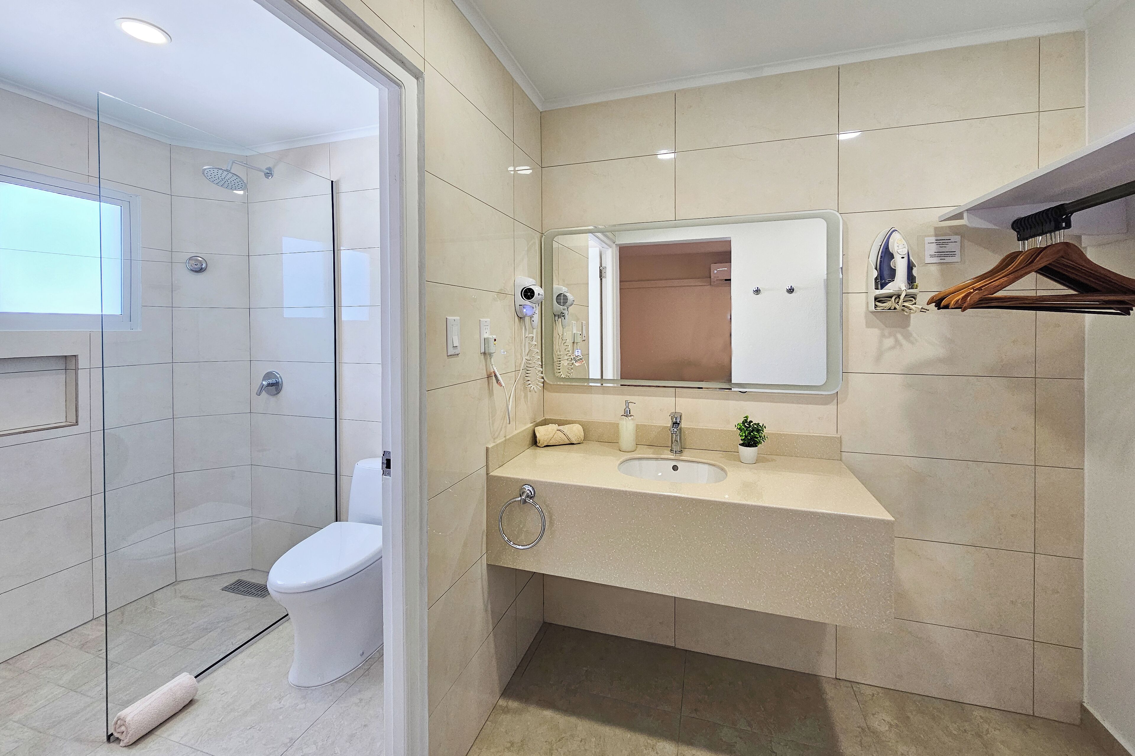 A modern bathroom with a glass-enclosed shower, a toilet, a sink with a mirror, and a towel rack.