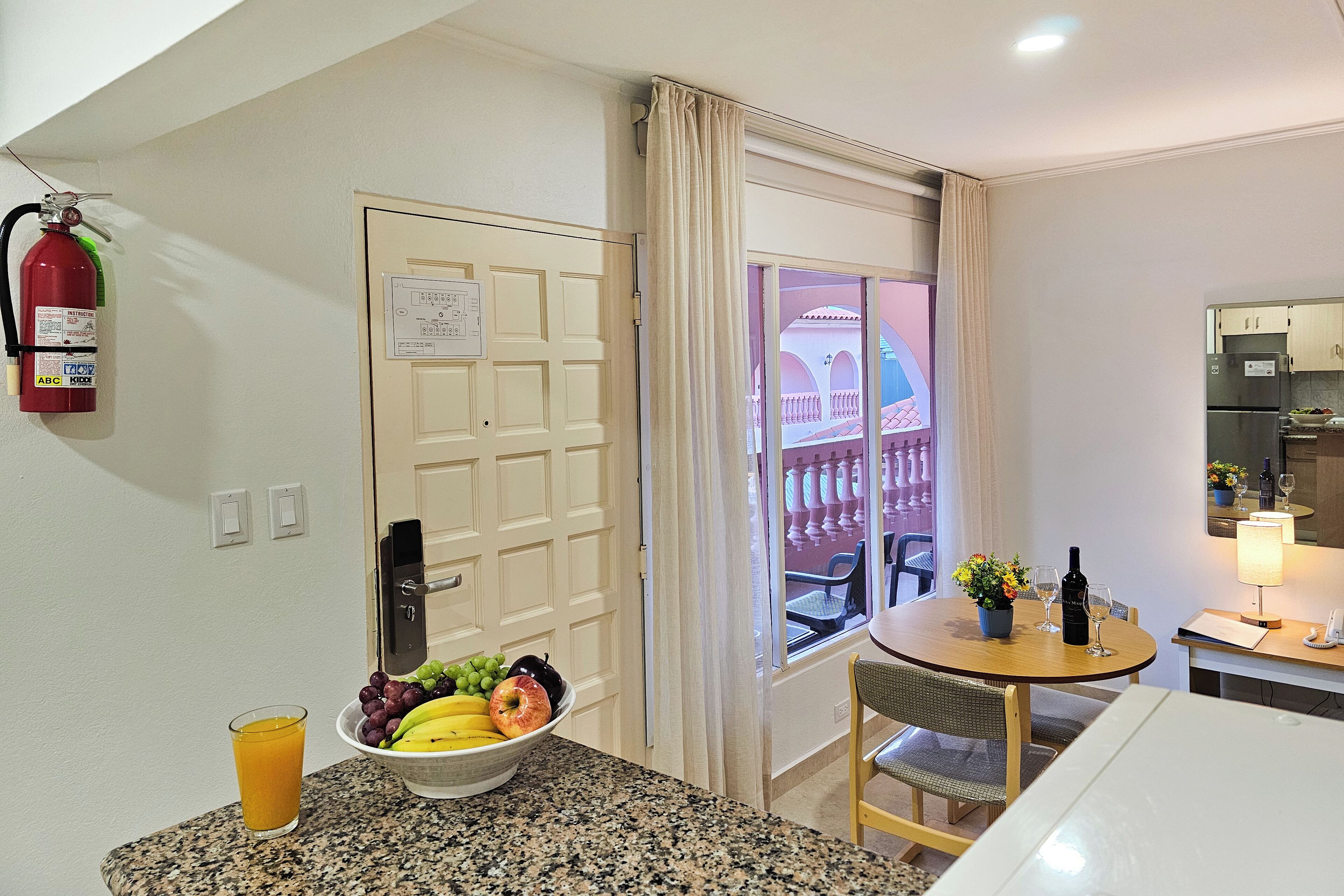 Une chambre d’hôtel comprenant un coin repas, un extincteur, une fenêtre avec vue et un coin cuisine.
