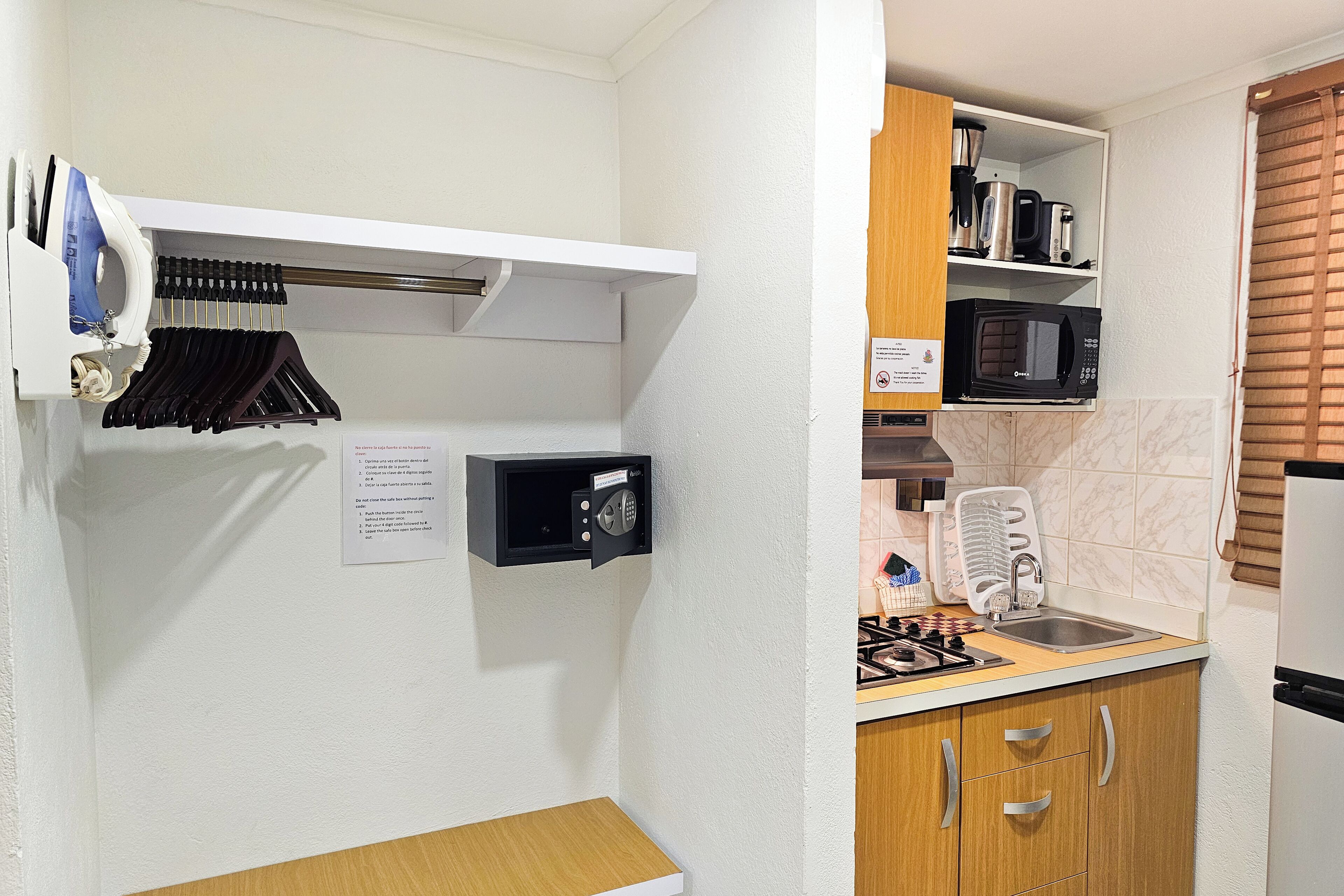 A compact kitchen with a microwave, stove, and a safe box with instructions.