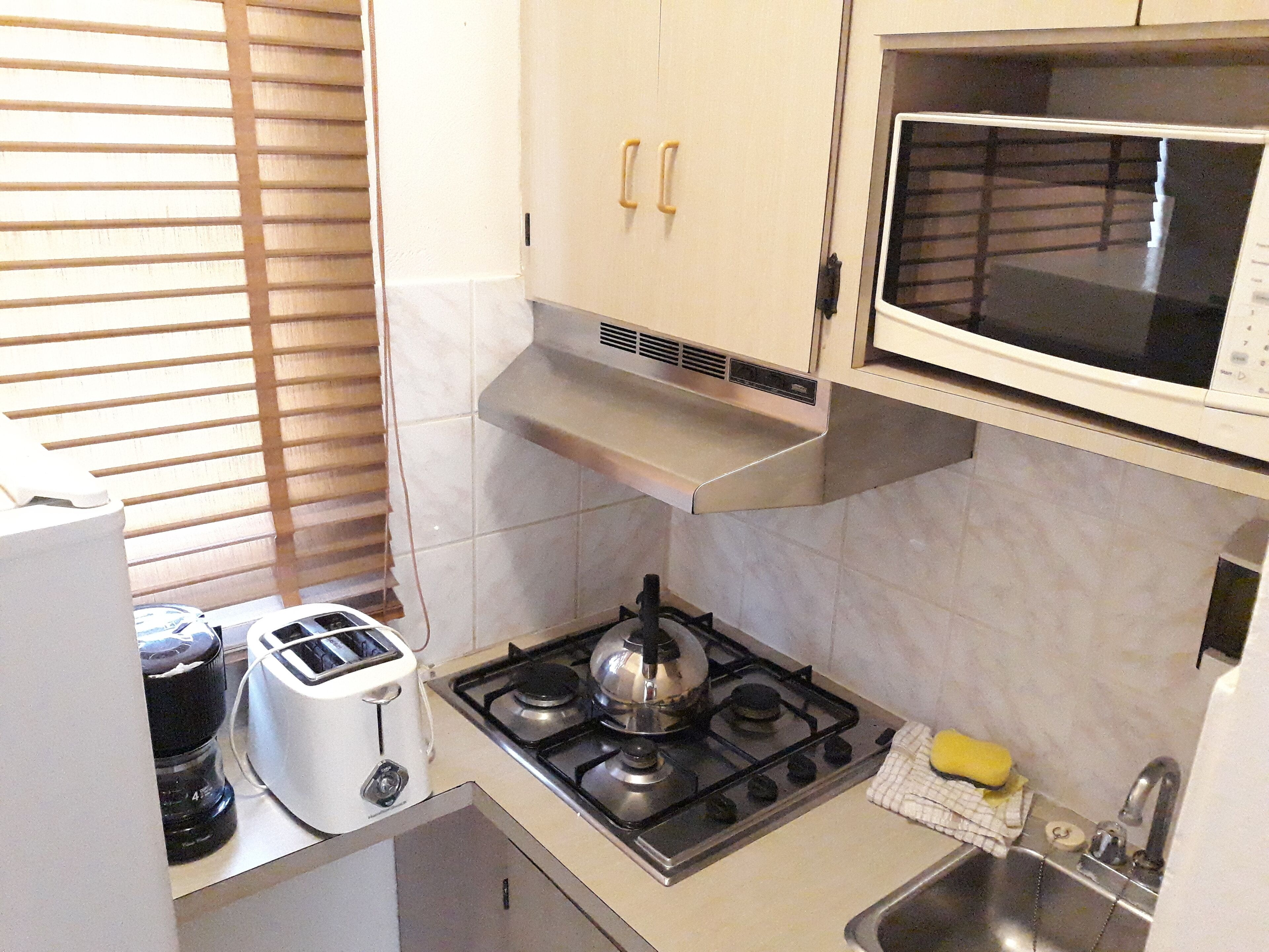 A compact kitchen with a gas stove, a microwave, and a toaster.