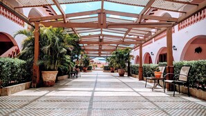A covered outdoor area with a tiled floor, wooden pergola, and potted plants. - Sasaki Apartments (Noord)