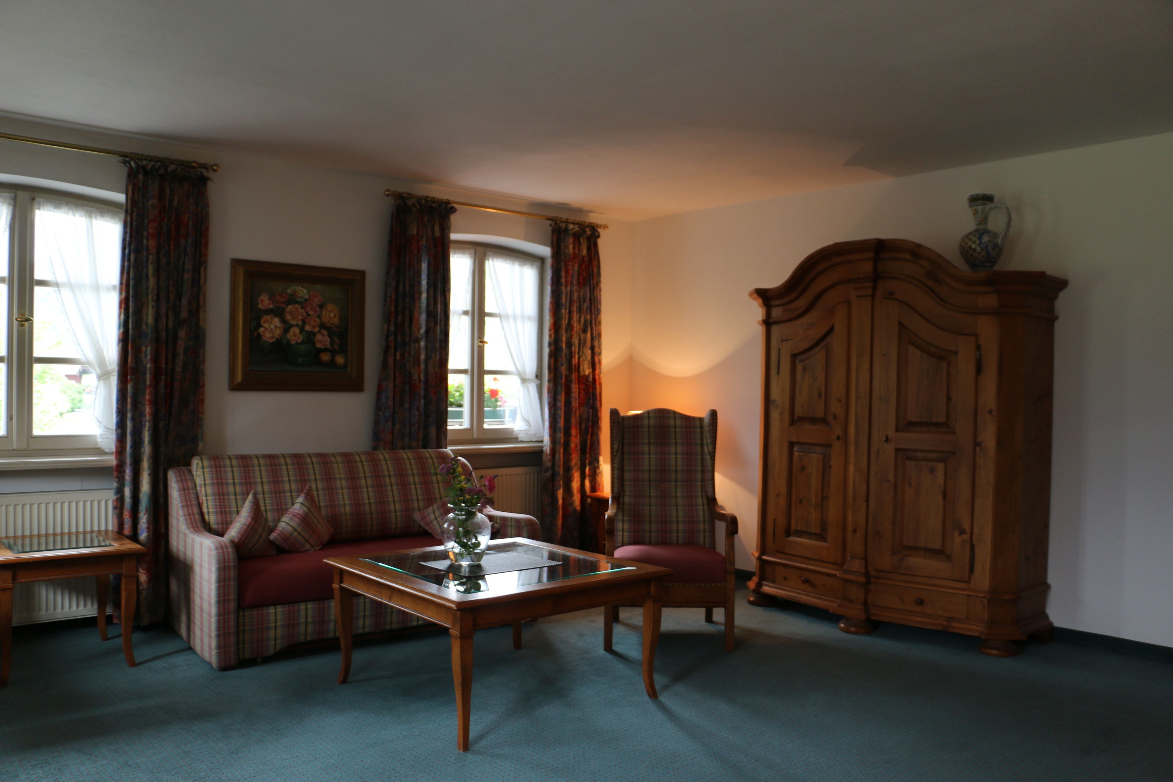 Una sala de estar con un sofá a cuadros, un mueble de madera y una mesa de centro de vidrio.