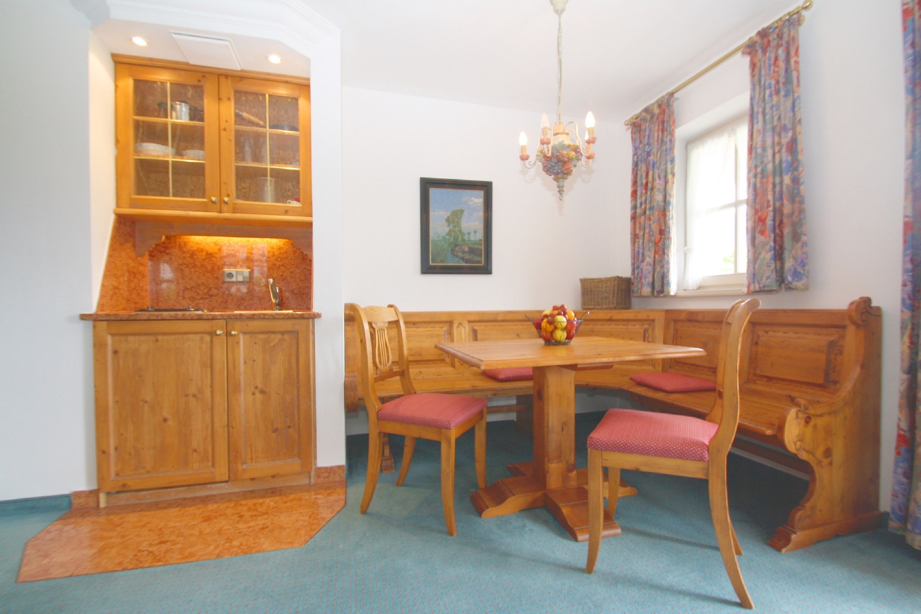 A dining area with wooden furniture, a chandelier, and a window with curtains.