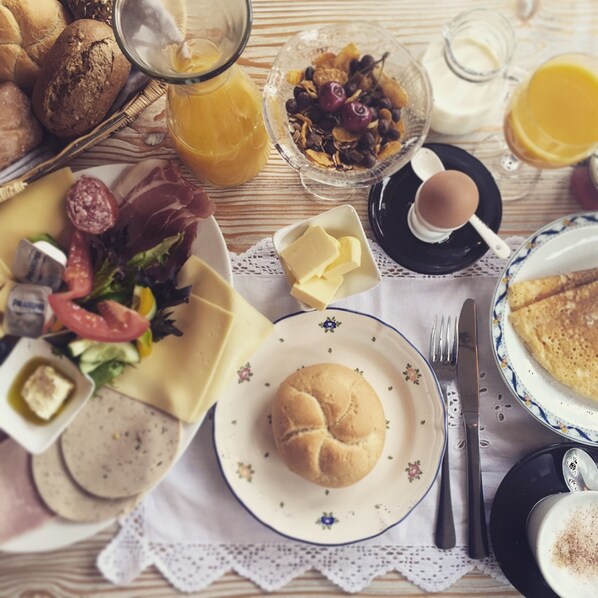 A breakfast table with various food items, including bread, eggs, and a drink.