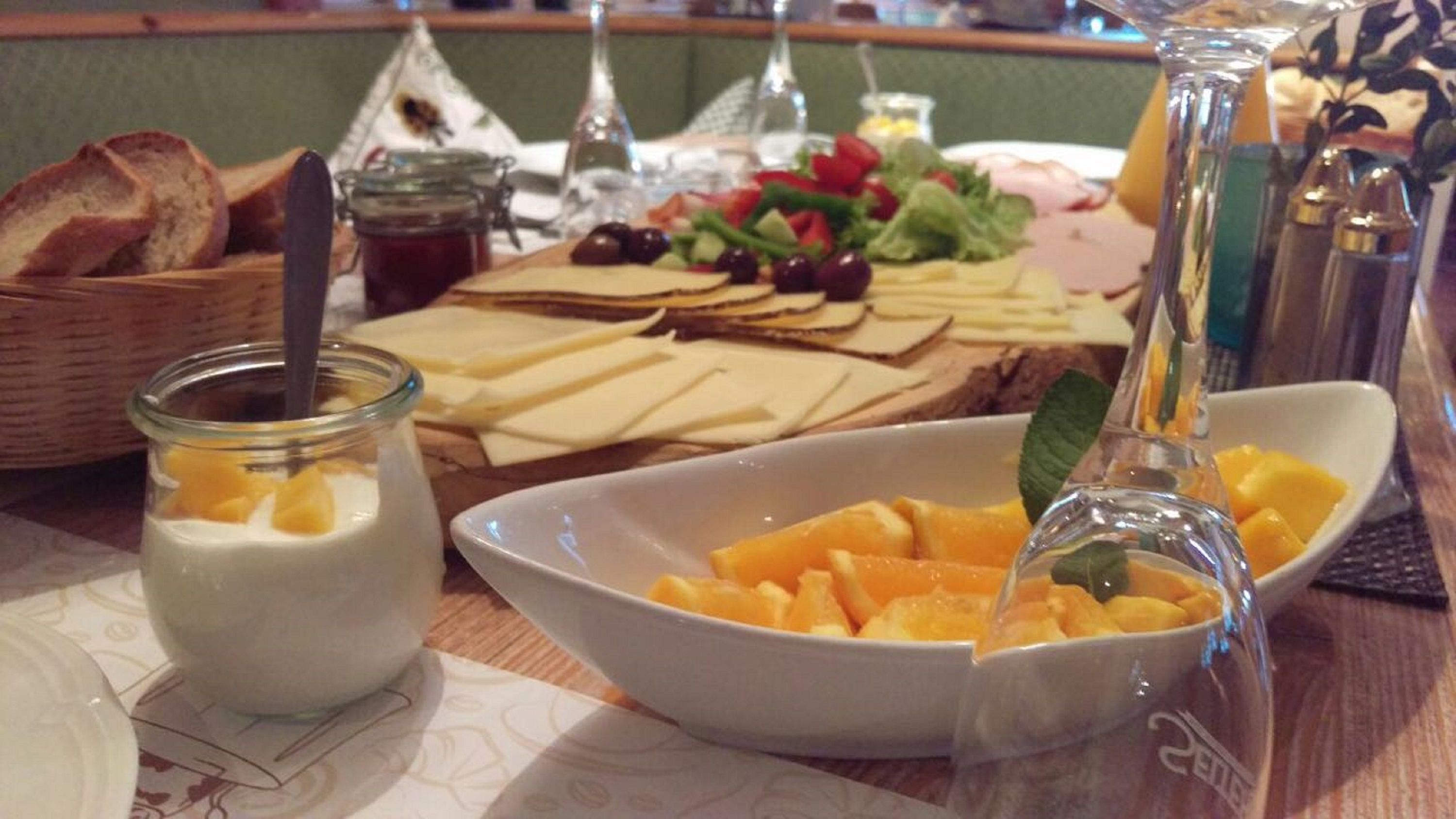 A breakfast buffet with various food items including cheese, fruits, and bread.