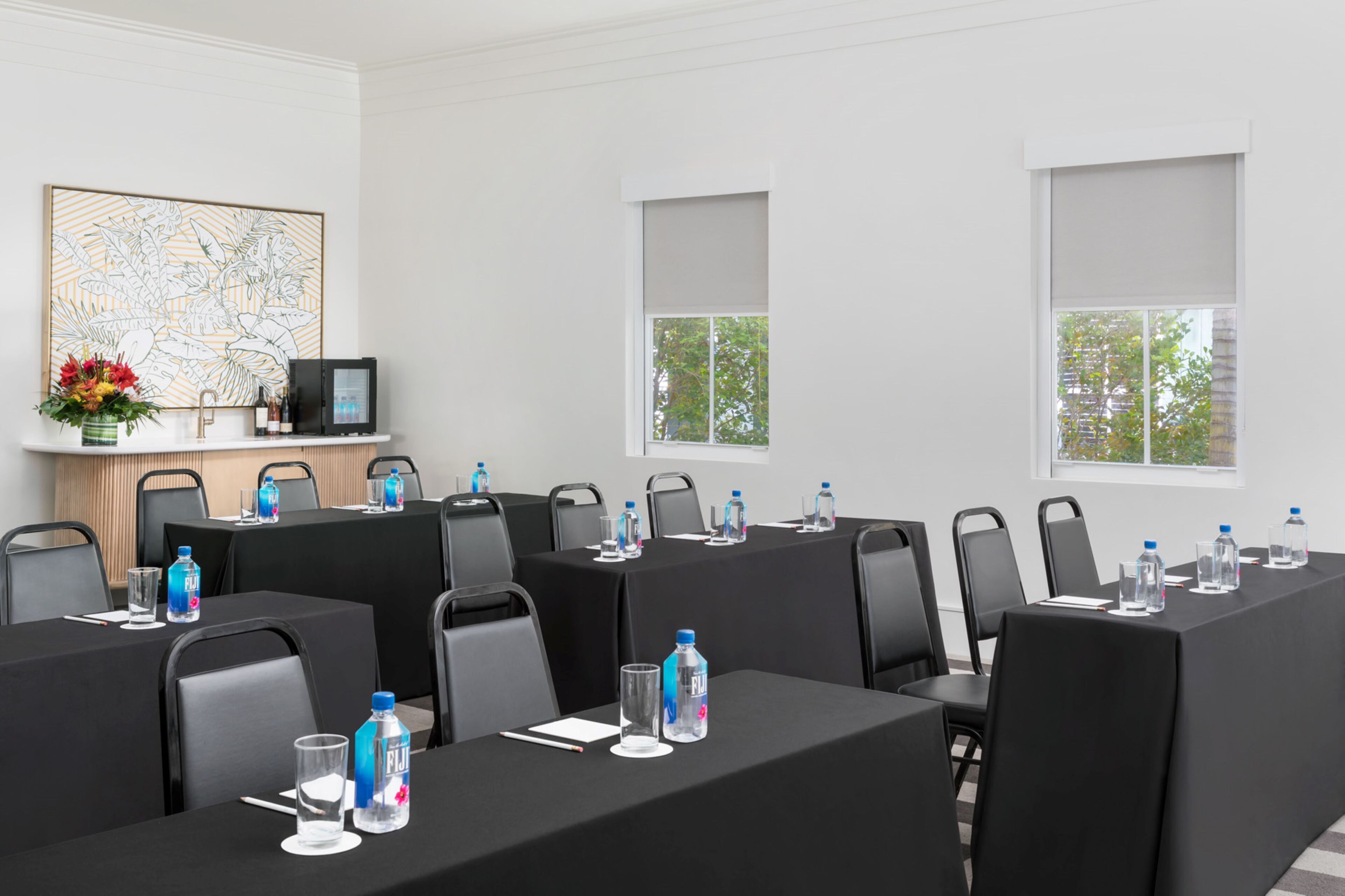 Une salle de conférence équipée de tables, de chaises, de bouteilles d’eau et d’une carte affichée au mur.