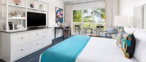 Une chambre d’hôtel avec un lit, un bureau, une télévision, un balcon donnant sur des palmiers et une fenêtre avec des rideaux.