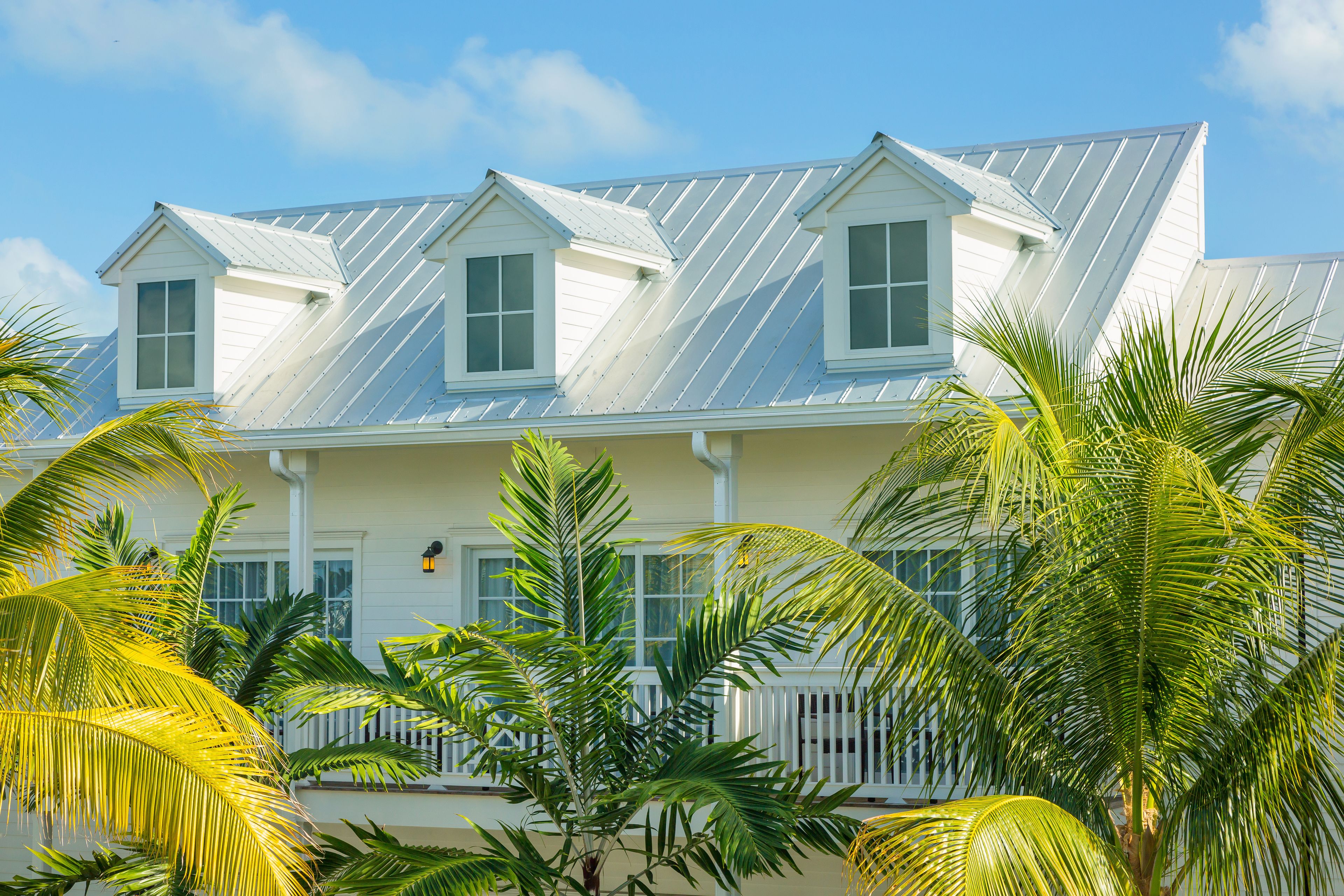 A coastal house with a gabled roof, white exterior, and a porch with a railing.