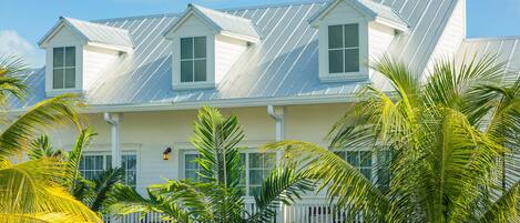 A coastal house with a gabled roof, white exterior, and a porch with a railing.