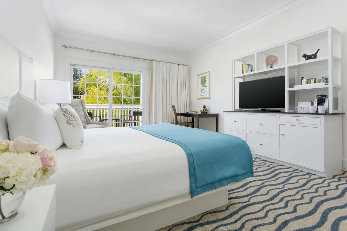 A hotel room with a bed, a desk, a television, and a bookshelf.