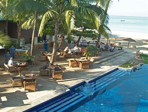 Área à beira da piscina com mobiliário de exterior e vista para o oceano.