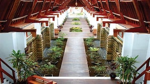 A wooden staircase with a central walkway, flanked by potted plants and a wooden bench. - Amata Resort & Spa (Ngapali)