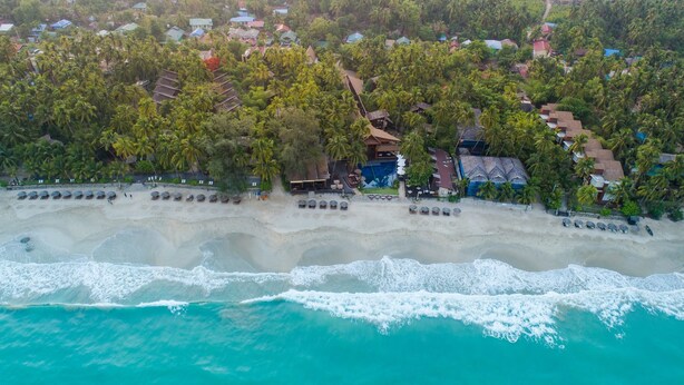 An aerial view of a beach resort with a long sandy beach, a pool area, and numerous palm trees. - Amata Resort & Spa (Ngapali)