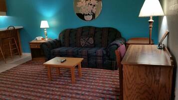 A living room with a sofa, a coffee table, a lamp, and a mirror on the wall.