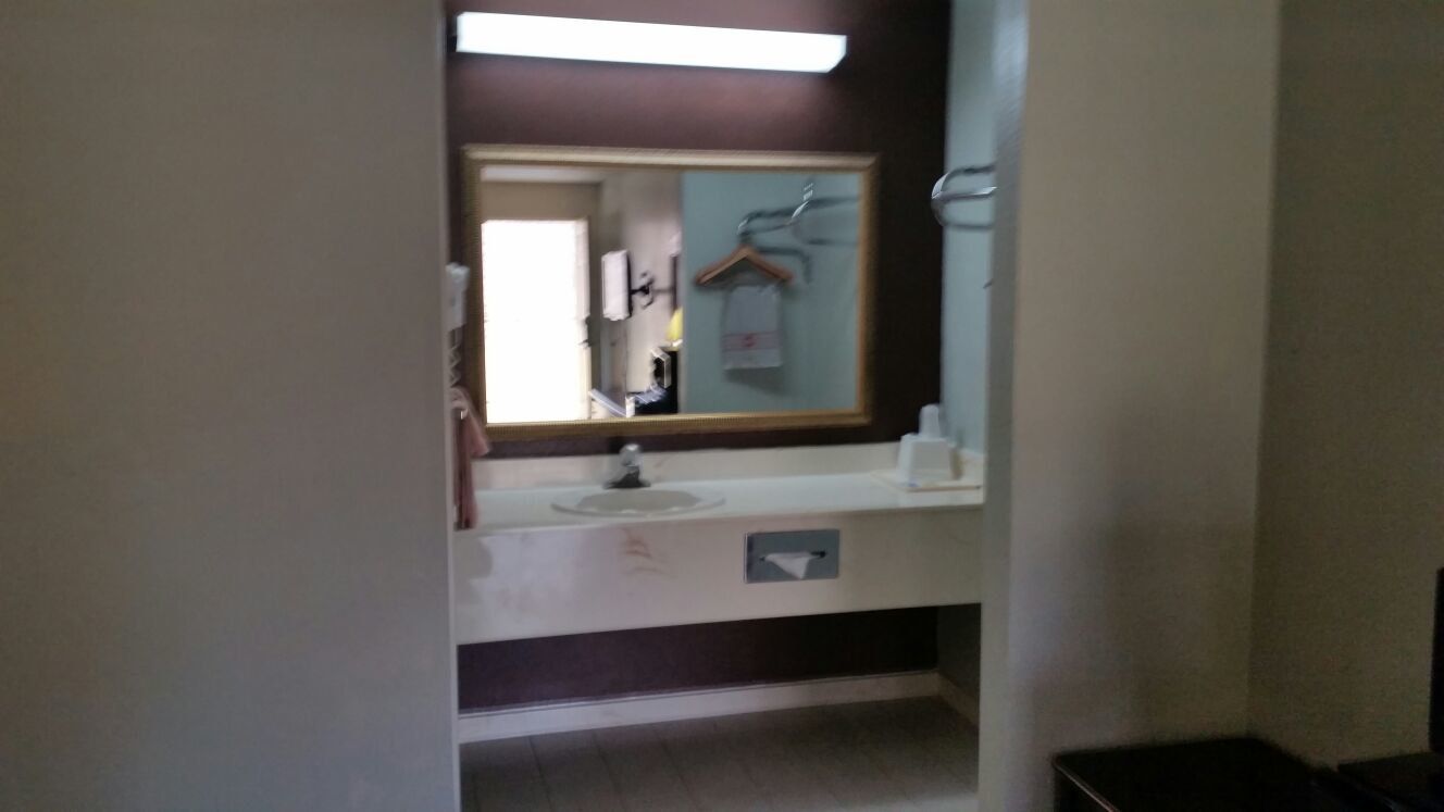 A bathroom with a mirror, sink, and towel rack.