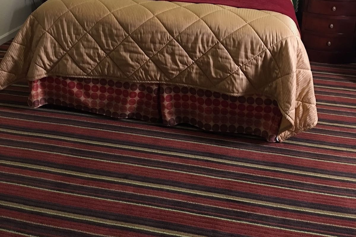 Quarto de hotel com uma cama grande, paredes verdes e duas luminárias de cabeceira.