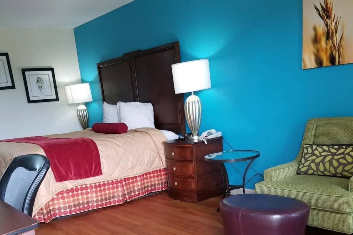 Quarto de hotel com cama, escrivaninha, cadeira, mesinha e sofá.