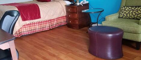 A hotel room with a bed, a desk, a chair, a small table, and a sofa.