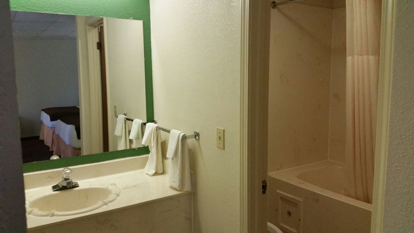 A bathroom with a sink, mirror, and shower.