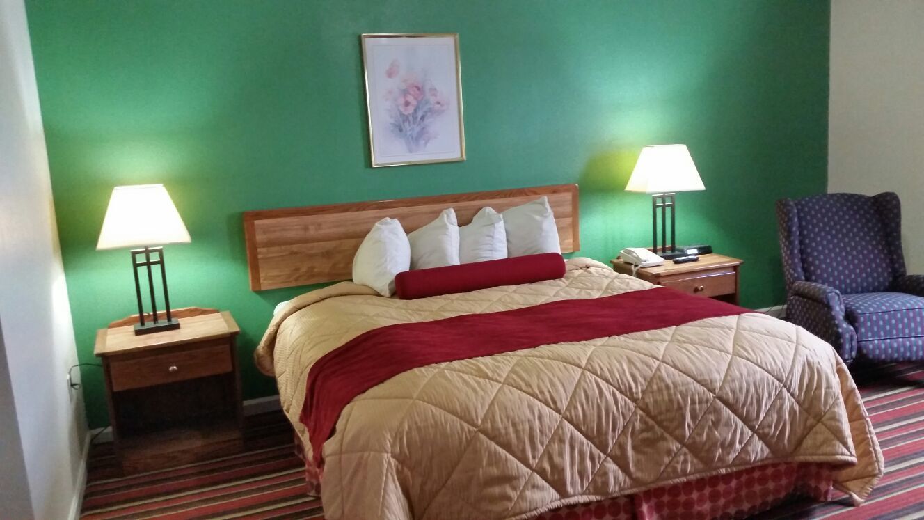 Ein Hotelzimmer mit einem Bett, zwei Nachttischen, einem Sessel und grünen Wänden.