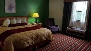 Een hotelkamer met een bed, een stoel, een lamp, een raam en een wandairconditioner.