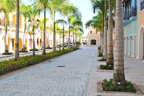 A cobblestone street lined with palm trees and buildings with balconies. - Fishing Lodge Cap Cana (Punta Cana)