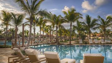 Una piscina al aire libre, sombrillas, sillones reclinables de piscina