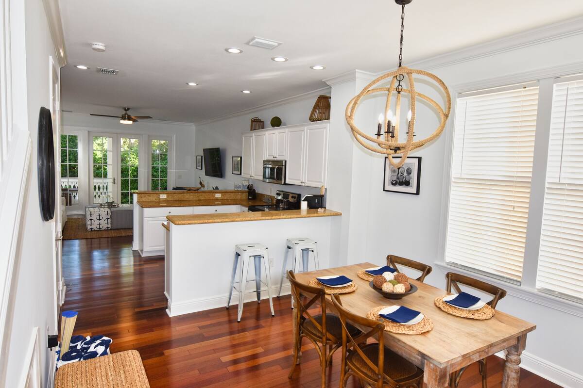 A spacious kitchen with white cabinets, a wooden island, and a dining area with a wooden table and chairs.