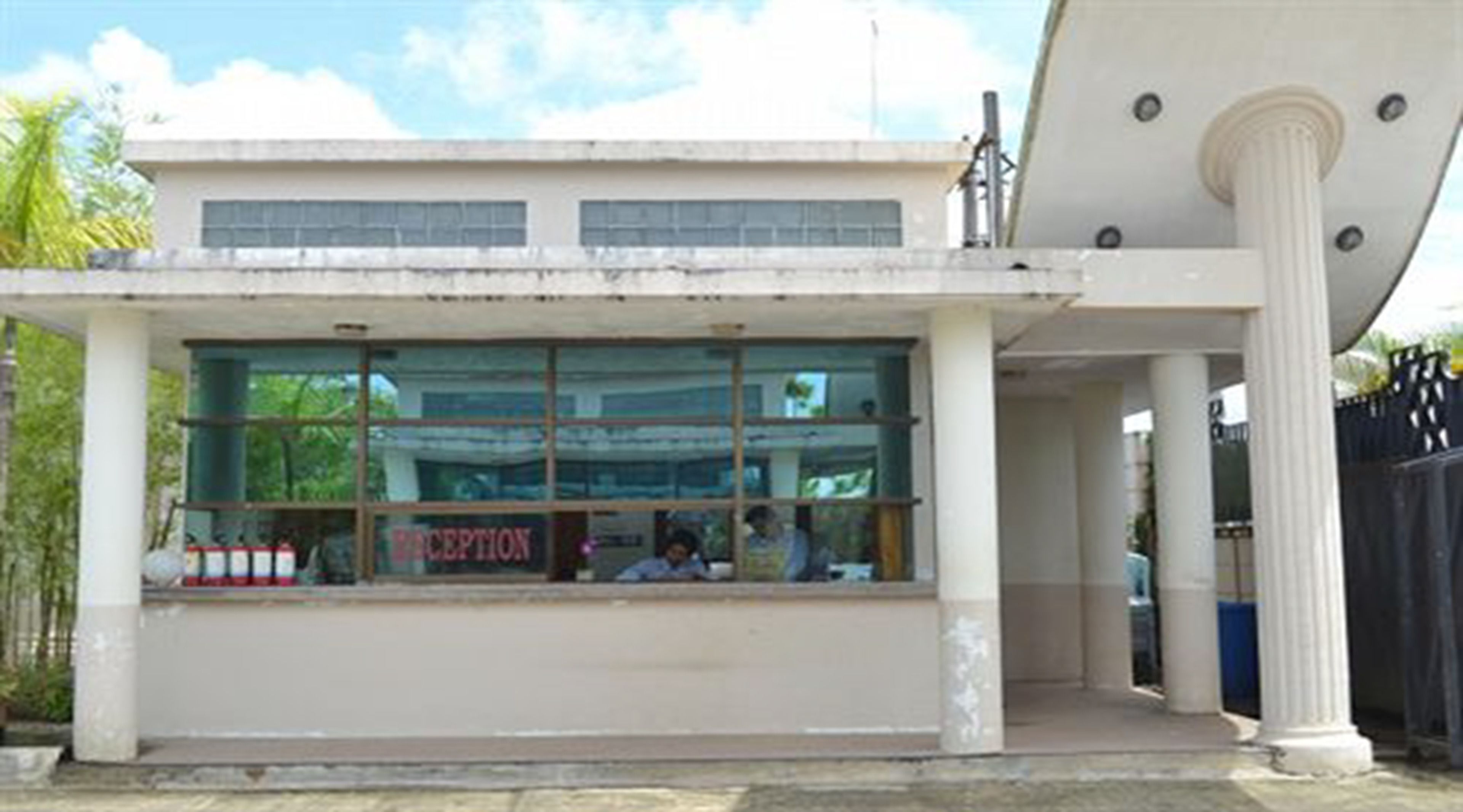 A reception area with a glass facade, a sign reading "RECEPTION," and a large column to the right.