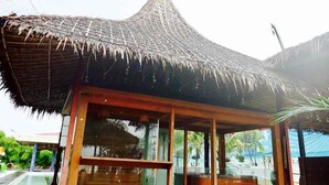 A thatched-roof structure with a glass enclosure, likely a part of a resort or hotel. - Excel River View Hotel (Thanlyin)