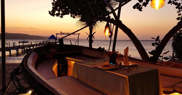 A beachside dining area with a table set for two, overlooking the sea. - Punta Rucia Lodge Hotel Boutique & Spa (Punta Rucia)