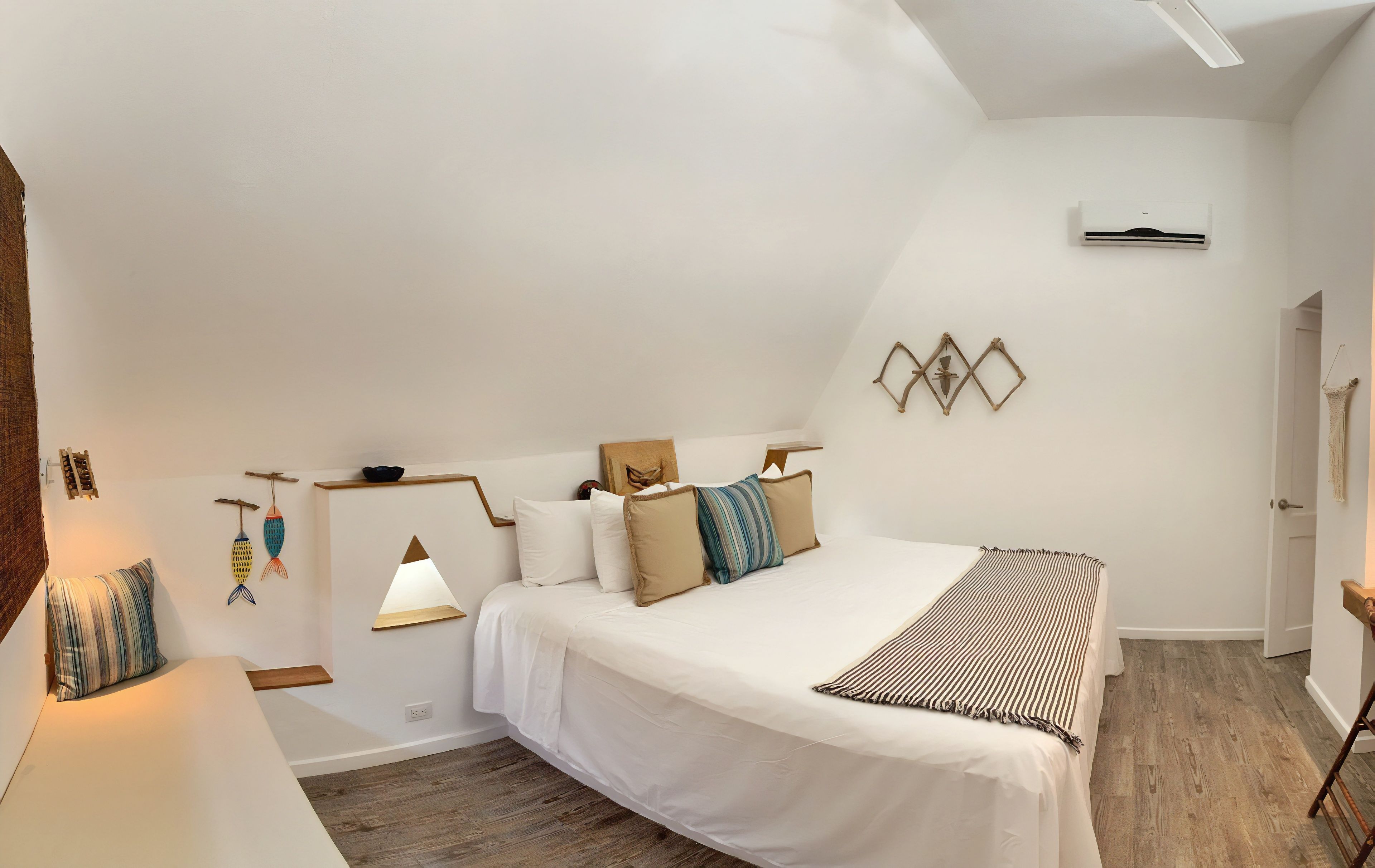 Un dormitorio con una cama grande, una mesita de noche, una lámpara colgante y un aire acondicionado instalado en la pared.