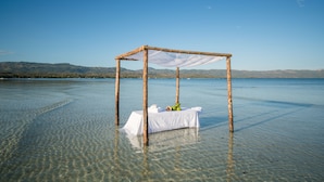 A wooden gazebo with a white table set up on a clear lake.