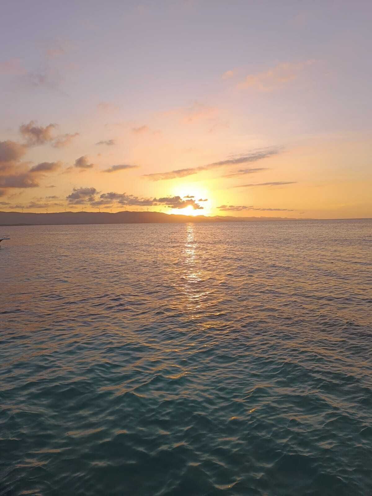 A sunset over a calm sea with a distant shoreline.