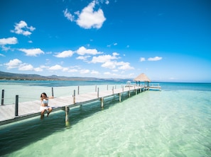 A clear view of a pier extending into turquoise waters with a thatched-roof structure at the end. - Punta Rucia Lodge Hotel Boutique & Spa (Punta Rucia)