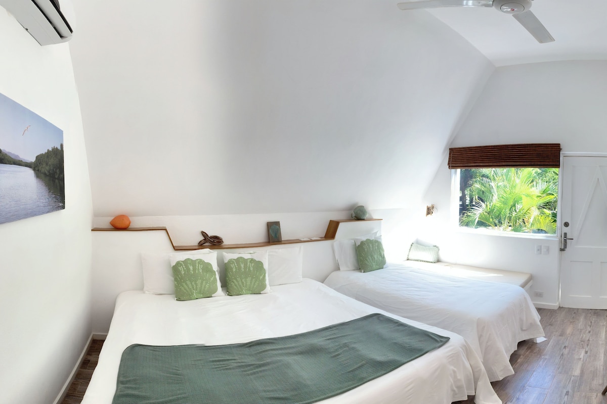 Un dormitorio con dos camas, un cuadro, una ventana con persianas y un ventilador de techo.