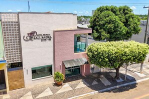 A hotel named 'Hotel Fousaba' with a modern facade, a large tree in front, and a small potted plant on the sidewalk. - Hotel Pousada Calliandra (Bonito)
