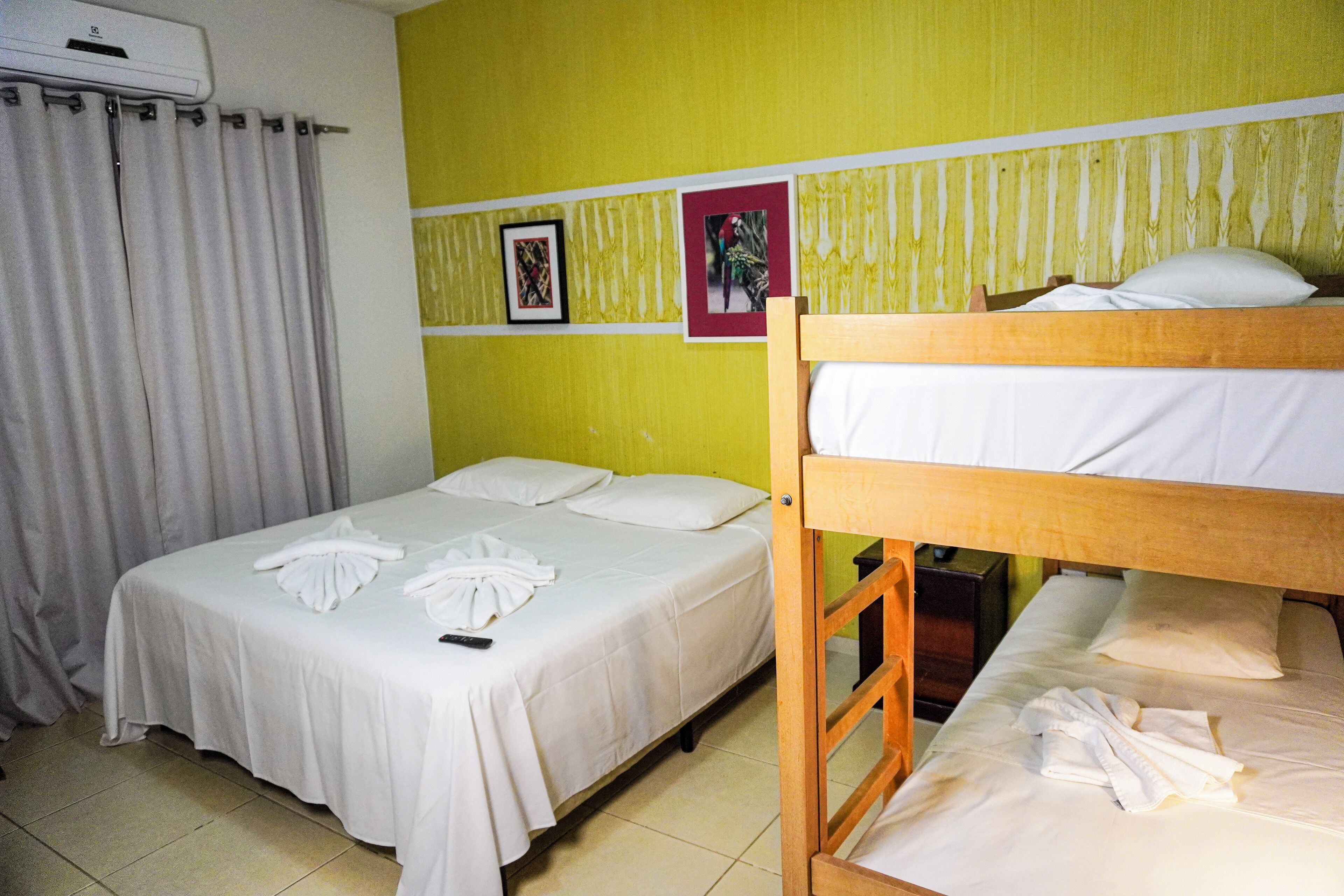 A hotel room with a bunk bed, a single bed, and a curtain.